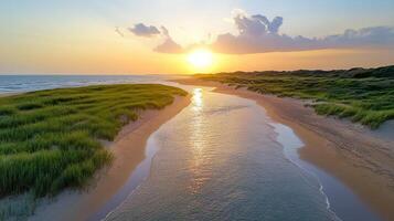 A river runs through a grassy beach at sunset photo
