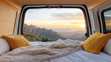 A bed in the back of a camper van with a view of mountains photo