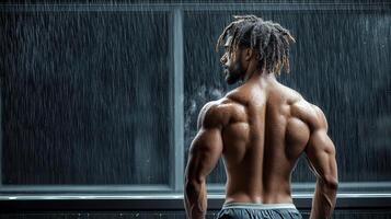 A man with a muscular back standing in front of a window photo