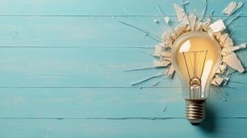 Light bulb breaking through a wall on a blue wooden background photo