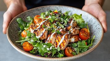 A person holding a bowl of salad with chicken and vegetables photo