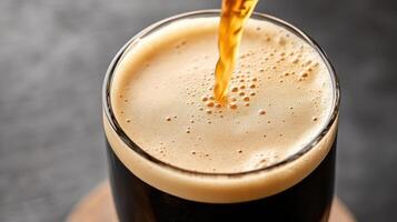 A glass of dark beer being poured into it photo