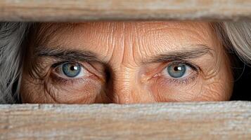 An older woman peeking out from behind a wooden wall photo