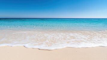 A sandy beach with a clear blue ocean and white waves photo