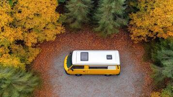 An aerial view of a camper van parked in the middle of a forest photo