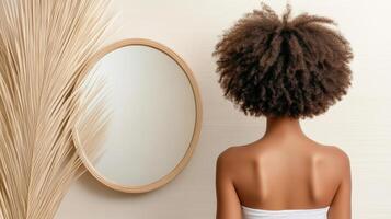 Back view of a young african american woman with afro hair looking at her reflection in photo