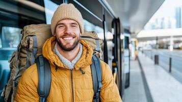 A man with a backpack is smiling and standing in front of a bus photo