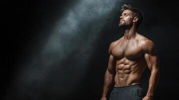 Muscular man posing in black background photo