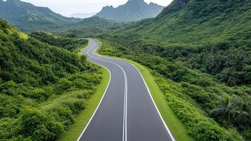 An empty road in the middle of a lush green valley photo