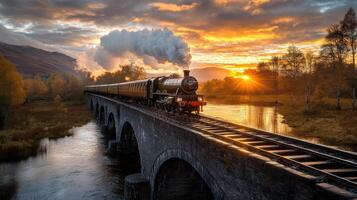 A steam train traveling over a bridge at sunset photo