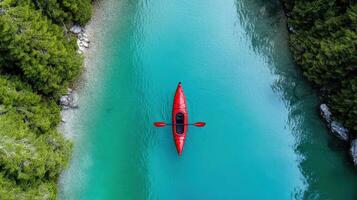 A red canoe is floating in a river surrounded by trees photo