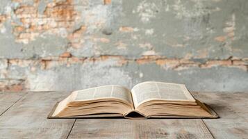 An open book on a wooden table in front of a grungy wall photo
