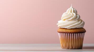 A cupcake with white frosting on top on a pink background photo