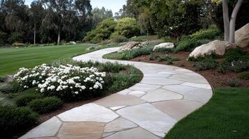 A stone pathway in a garden with flowers and trees photo
