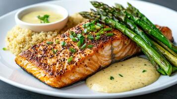 A plate with salmon, asparagus and a sauce photo