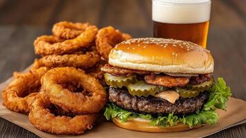 A hamburger and onion rings sit on a paper plate photo