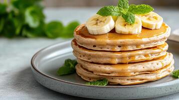 A stack of pancakes with bananas and mint leaves photo