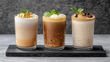 Three different types of milkshakes are shown on a black tray photo