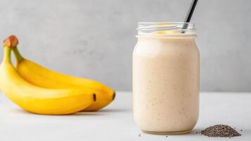 A smoothie in a glass with a straw next to a banana photo