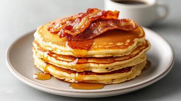 A stack of pancakes with bacon and syrup photo