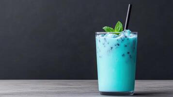 Blue iced drink with black straw on wooden table photo