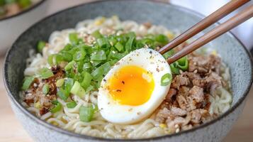 A bowl of noodles with an egg and chopsticks photo