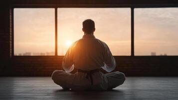 A man in karate gear sitting in front of a window photo