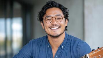 A man with glasses and a guitar smiling photo