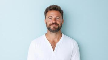 A man with a beard and white shirt standing in front of a blue wall photo