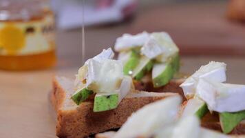 Toasts topped with sliced green pear, soft white cheese and honey drizzle, highlighting gourmet snack preparation, fresh ingredients and sweet savory combination video