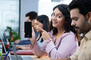 Bank Employee Female Sitting On Office Desk Pointing On Mobile Phone Screen photo