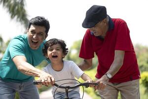 Curious Boy Learning Bicycle With Father And Grandfather photo