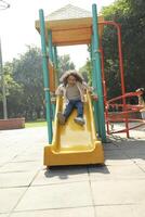 Happy Boy Sliding On The Slide In The Park photo