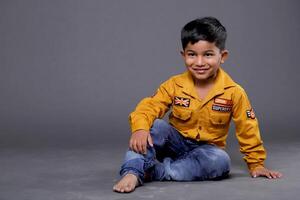 A Happy Boy Sitting On Floor Is Posing In Front Of The Camera photo