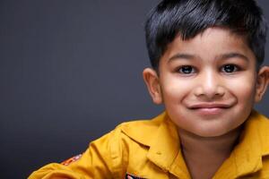 A Little Smiling Boy Is Posing While Looking At The Camera photo