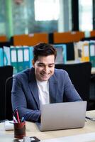 Innovative Indian Businessman In A Suit Grinning While Viewing A Laptop Screen photo
