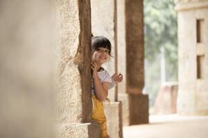 Small Kids Hiding Behind Ancient Column photo