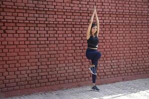 Fit Lady Standing On One Leg With Both Hands Up While Practising Body Balance photo