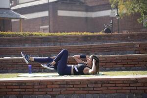 Happy Female Doing Elbow To Knee Crunch At Park photo