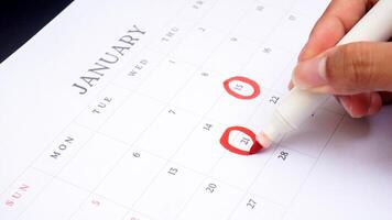 Red circle marked on a calendar at 15 and 21 of January isolated on black background for an important day photo