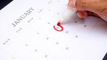 Red circle marked on a calendar at 15 of January isolated on black background for an important day photo