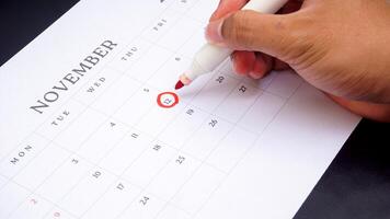 Red circle marked on a calendar at 12 of November as symbol of important day isolated on black background photo