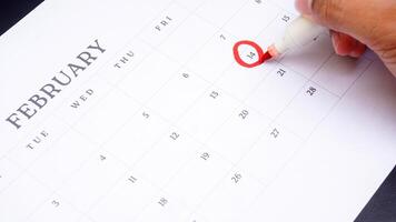 Red circle marked on calendar at 14 of February as symbol of valentine day isolated on black background photo