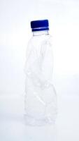 Empty crumpled plastic bottle with blue bottle cap isolated on white background photo