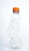 Empty crumpled plastic bottle with orange bottle cap isolated on white background photo