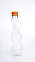 Crumpled and empty plastic water bottle with orange bottle cap isolated on white background photo