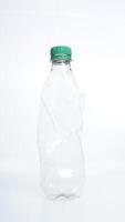 Empty crumpled plastic bottle with green bottle cap isolated on white background photo