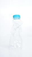 Crumpled used plastic water bottle with light blue bottle cap isolated on white background photo