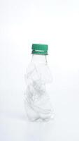 Crumpled and empty plastic water bottle with green bottle cap isolated on white background photo