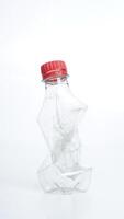 Crumpled used plastic water bottle with red bottle cap isolated on white background photo